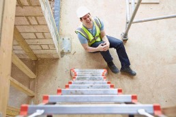 male construction worker holding his knee