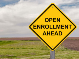 a yellow sign in an open area that says open enrollment ahead