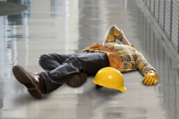construction working laying down on back holding head in pain