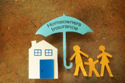 paper cutouts of umbrella with homeowners insurance written on it covering family and home