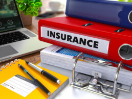 binder labeled insurance next to other business supplies