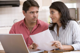 man and woman physical document while using laptop